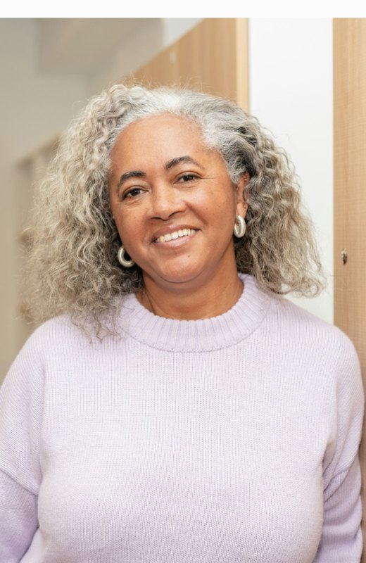 A smiling woman with silver curly hair, representing facial volume restoration after weight loss at Florida Aesthetics and Wellness