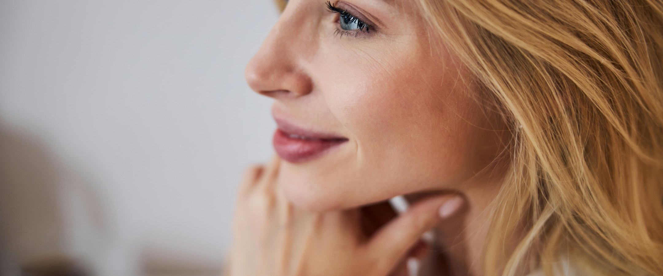 A woman resting her hand against her jaw, her hands and skin in soft natural light